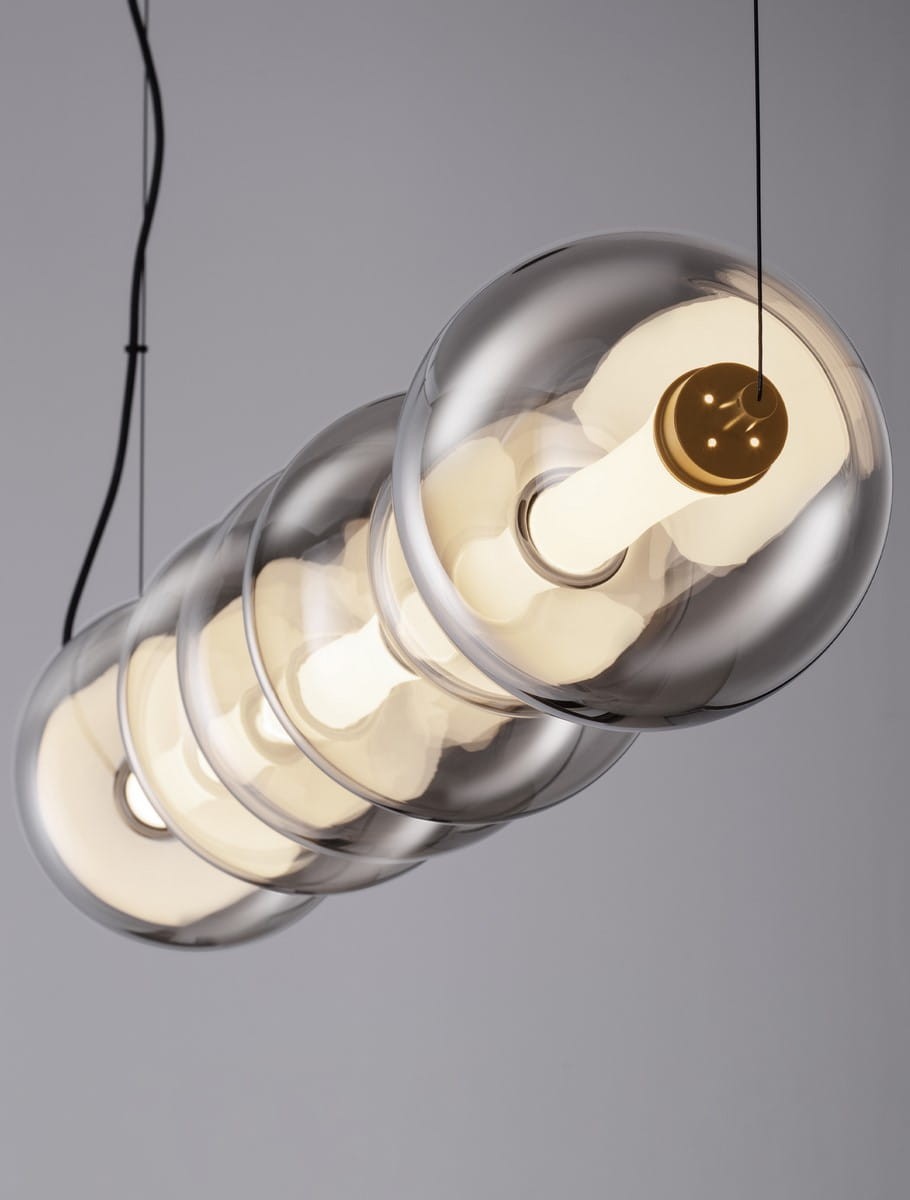 Lampa wisząca Luis z czarnym przewodem, składająca się z trzech przezroczystych kloszy w kształcie kul, w których znajdują się źródła światła LED. Klosze emitują ciepłe, białe światło, tworząc nowoczesny efekt oświetleniowy.