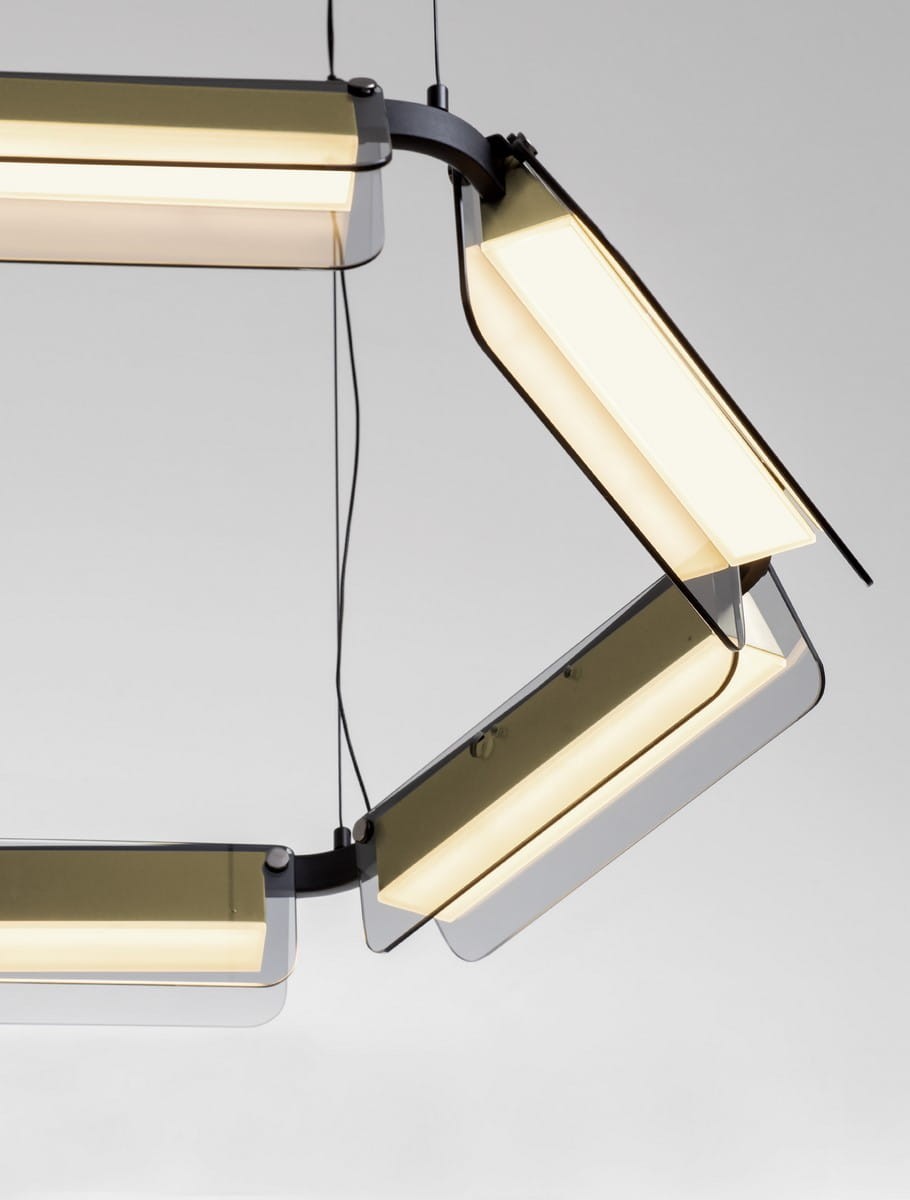 Lampa wisząca Roca z sześcioma źródłami LED, o mocy 39W, w kolorze czarnym z złotymi akcentami. Ułożona w dynamiczny kształt, z przezroczystymi kloszami, zawieszona na cienkich linkach. Tło jasne, podkreślające elegancki design.