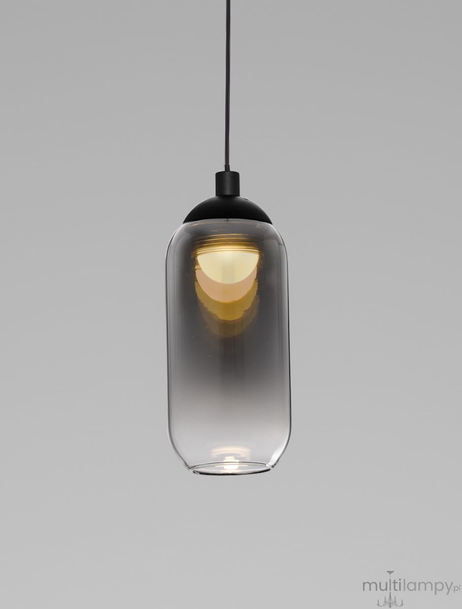 Lampa wisząca Toay w kolorze czarnym z kloszem ze szkła w kształcie cylindrycznym, zawieszona na czarnym przewodzie. Źródło światła LED 1x6W, z widocznym ciepłym światłem w dolnej części klosza. Tło szare, proste.