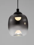 Czarna lampa wisząca Toay z kloszem z szarego szkła, zawieszona na czarnym przewodzie. Wewnątrz znajduje się żarówka LED o mocy 6W. Kształt klosza jest zaokrąglony, z połyskującą powierzchnią. Tło jasnoszare.