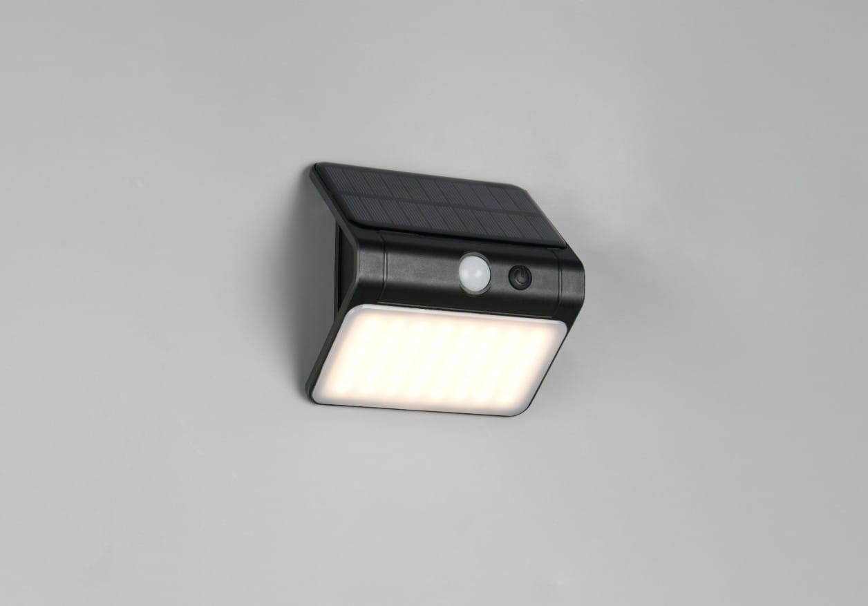 Kinkiet zewnętrzny Olinda w kolorze czarnym, zintegrowany panel solarny i czujnik ruchu. Wbudowana lampa LED 1x2,5W. Produkt zamontowany na ścianie, z widoczną jasną powierzchnią emitującą światło i czujnikiem na przedniej ściance.