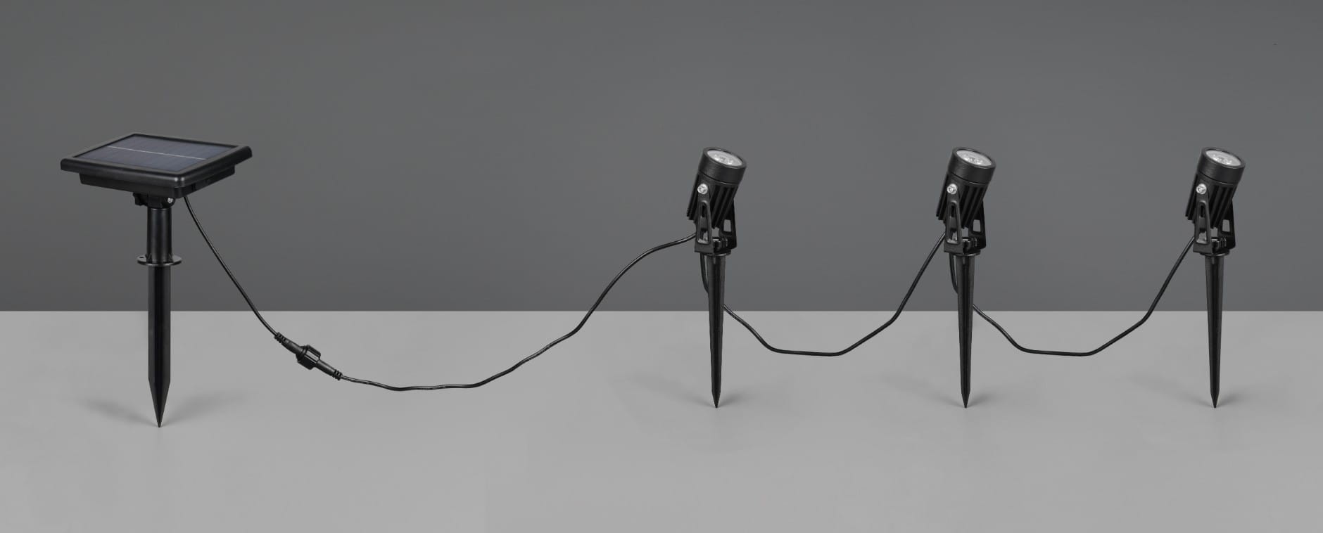 Zestaw trzech opraw dogruntowych solarnych Obidos w kolorze czarnym, składający się z panelu słonecznego oraz trzech lamp LED (1,5W, 4000K). Produkt ustawiony w linii, z widocznym kablem łączącym. Oprawy mają stożkowate podstawy do montażu w ziemi.
