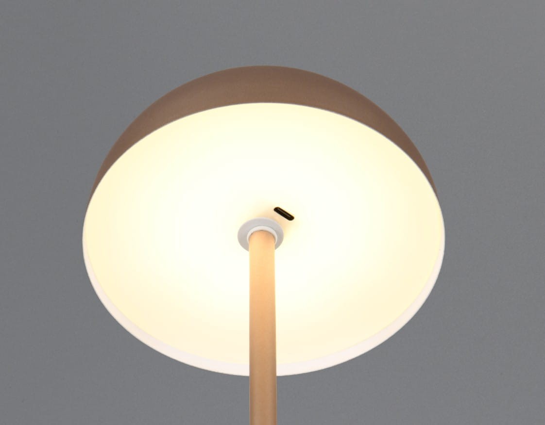 Lampa stołowa Munoz w kolorze kawowym z jedną żarówką LED 1,3W. Okrągły klosz z matowego tworzywa, zamontowany na cienkim, prostym stelażu. Widoczny port ładowania USB. Ujęcie z góry, pokazujące klosz i stelaż.