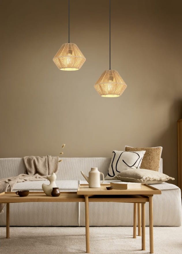 Lampa wisząca Lucille w kolorze czarnym i brązowym, z kloszem w kształcie diamentu, zawieszona na czarnym przewodzie. W tle jasna ściana i stylowy, jasny salon z kanapą i drewnianym stolikiem.