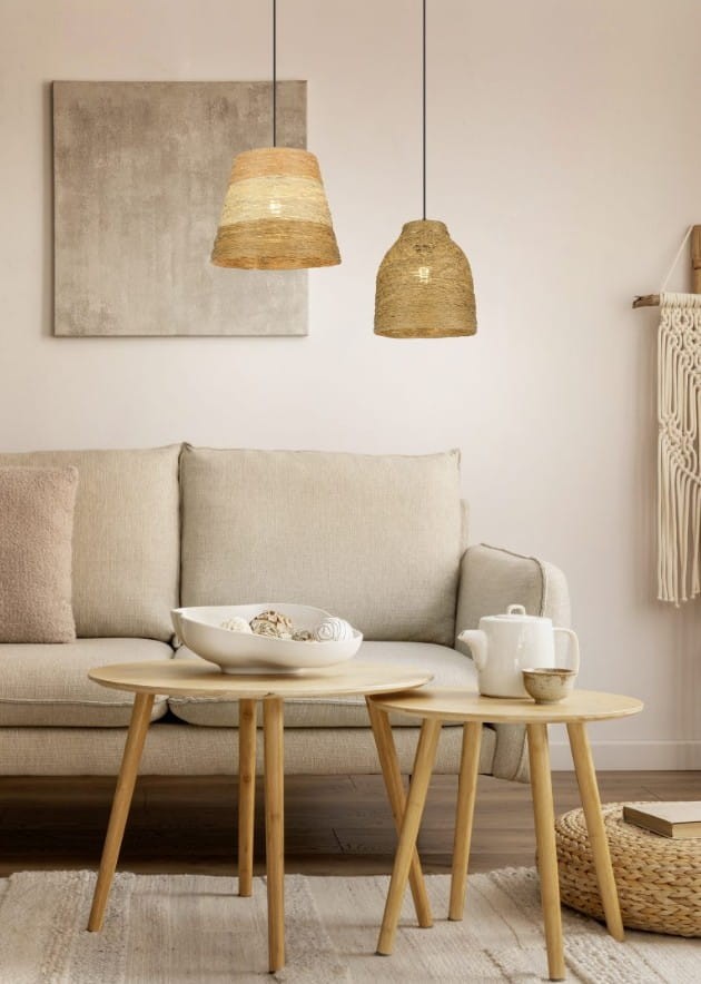 Lampa wisząca Joeline z jedną oprawą E27, o kształcie stożkowym, w kolorze czarnym i brązowym. Zawieszona nad kanapą w jasnym wnętrzu, z naturalnym wykończeniem, z widocznymi elementami dekoracyjnymi w otoczeniu.