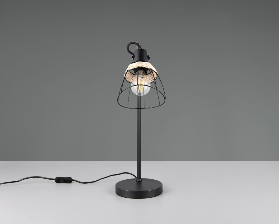 Lampa stołowa Jarome w kolorze czarnym z naturalnym kloszem. Konstrukcja z metalowym stelażem i okrągłą podstawą. Klosz w formie siatki, eksponujący żarówkę E27. Ujęcie z boku na jednolitym tle. Kabel z przełącznikiem widoczny z lewej strony.