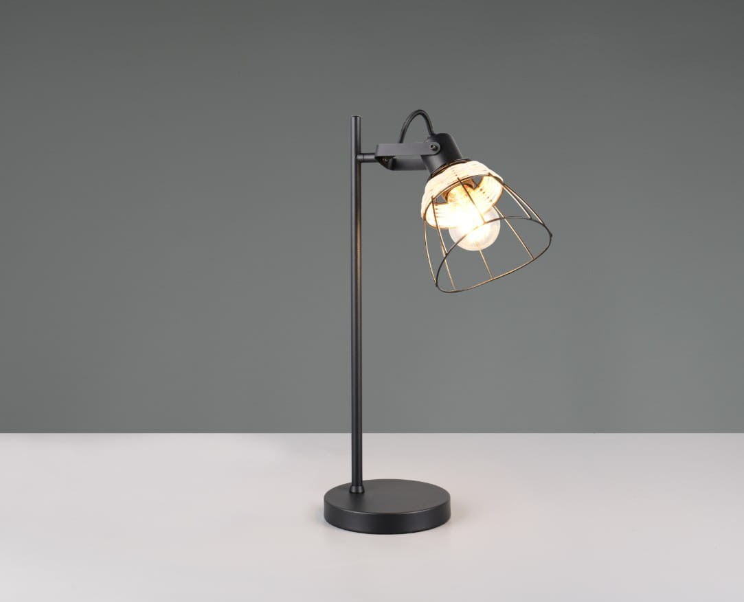 Lampa stołowa Jarome w kolorze czarnym z naturalnym kloszem. Posiada metalowy stelaż z okrągłą podstawą oraz szklany żarówkę osłoniętą siatką. Ujęcie z boku, eksponujące detal klosza i stylowy design. Tło neutralne, szare.