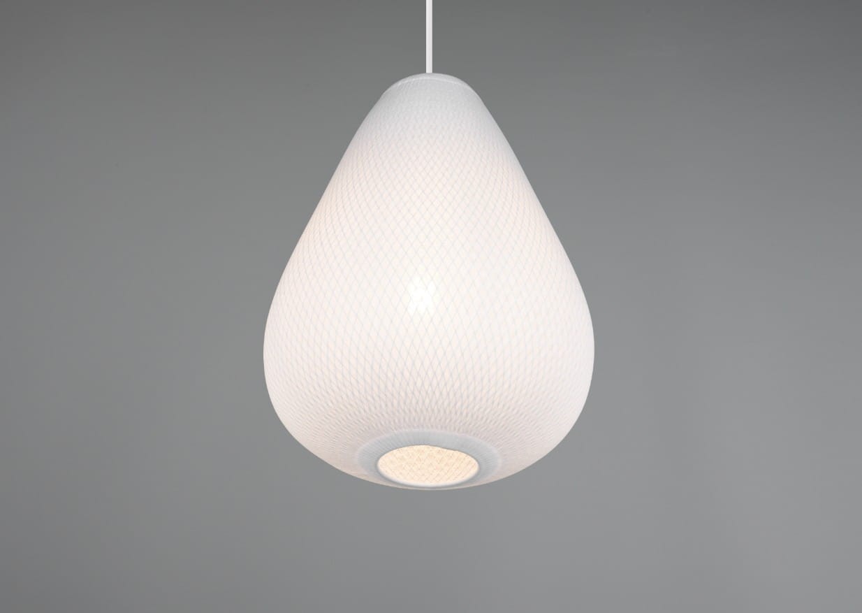 Lampa wisząca Janine w białym kolorze, o kształcie kropli, z teksturowaną powierzchnią. Zawieszona na białym przewodzie, z widocznym gniazdem na żarówkę E27. Tło w odcieniu szarości, podkreślające minimalistyczny design.