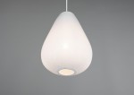 Lampa wisząca Janine w białym kolorze, o kształcie kropli, z teksturowaną powierzchnią. Zawieszona na białym przewodzie, z widocznym gniazdem na żarówkę E27. Tło w odcieniu szarości, podkreślające minimalistyczny design.