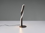 Lampa stołowa Ginko w kolorze czarnym z LED o mocy 10W. Ma nowoczesny, spiralny kształt z podświetloną krawędzią. Ustawiona pionowo na okrągłej podstawie, z widocznym kablem zasilającym. Tło w odcieniu szarym.