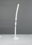 Lampa podłogowa Ginko w kolorze białym, z zakrzywionym kształtem i jedną oprawą LED o mocy 19W. Stoi na okrągłej podstawie, z przewodem zasilającym i włącznikiem widocznym na stole. Tło szare, proste.