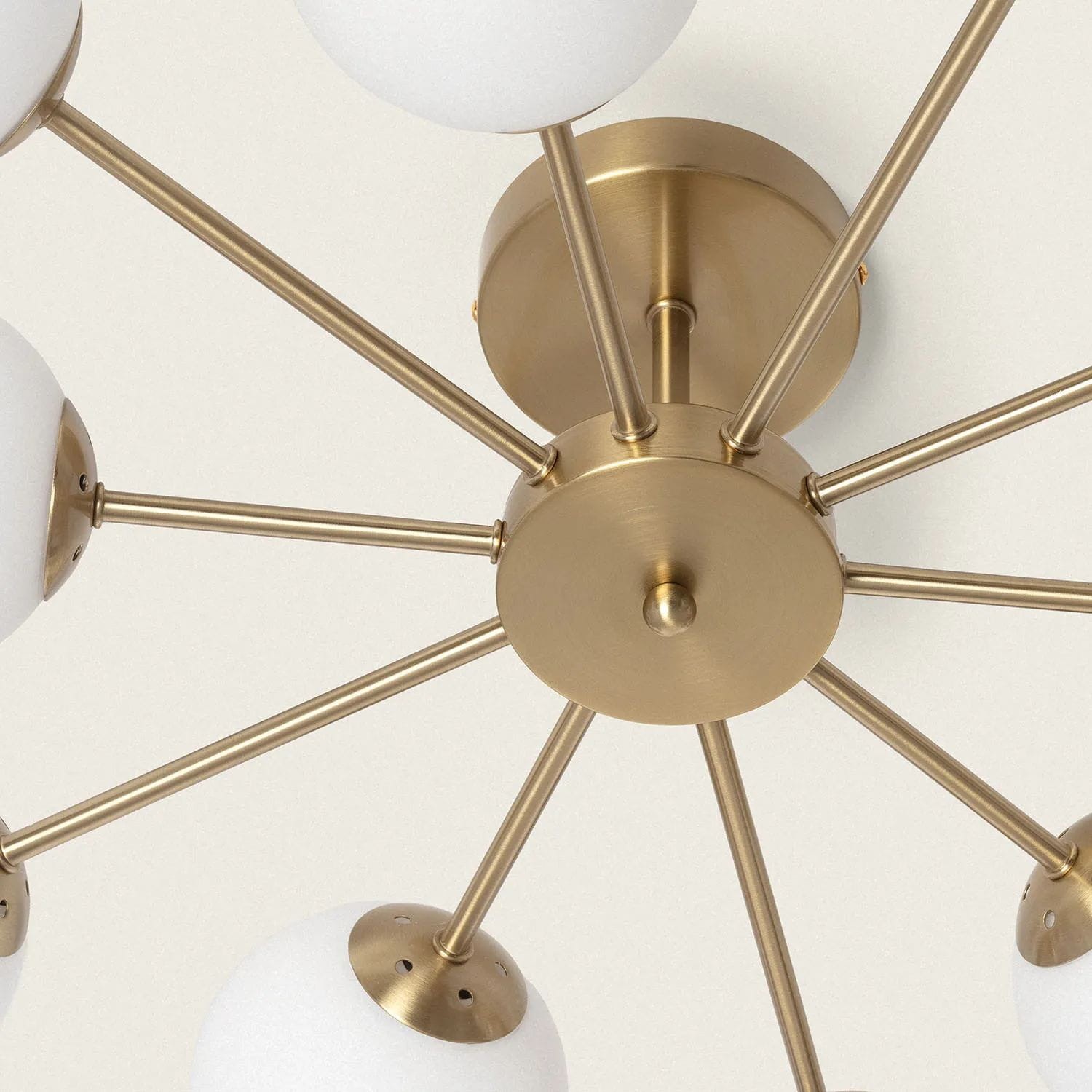 Złota lampa sufitowa Abruzzo-Milano z dziesięcioma oprawami G9. Konstrukcja z metalowymi ramionami i okrągłymi, białymi kloszami. Ujęcie z dołu, ukazujące detale mocowania i rozmieszczenie źródeł światła. Tło jasne.