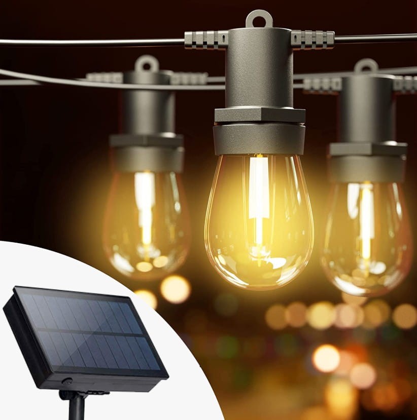 Girlanda solarna o długości 20 m w kolorze czarnym, z 20 żarówkami LED E27 1W. Widoczne żarówki w kształcie kropli, zawieszone na metalowej linki. Obok panel słoneczny, zapewniający zasilanie. Tło w rozmytych kolorach, tworzące atmosferę.