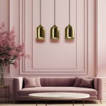 Lampa wisząca Nilo 3xGU10 w kolorze złotym, składająca się z trzech metalowych kloszy w kształcie dzwonu, zawieszonych na czarnych przewodach. Produkt umieszczony nad różowym sofą w eleganckim wnętrzu z różowymi ścianami.