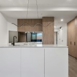 Lampa wisząca LED Zigzag o mocy 13W w kolorze białym, z falistym kształtem, zawieszona nad białym blatem kuchennym. W tle drewniane szafki i lustro odbijające widok z okna. Ujęcie frontalne, ukazujące nowoczesny design oświetlenia w aranżacji wnętrza.