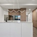 Lampa wisząca LED Zigzag w białym kolorze o mocy 13W, zawieszona w nowoczesnej kuchni. Ujęcie z góry ukazuje falisty kształt lampy oraz minimalistyczne wnętrze z drewnianymi szafkami i blatem z jasnego kamienia.