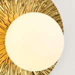 Kinkiet Sun S w kolorze złotym, z okrągłym kloszem z mlecznego szkła. Żłobiona, teksturowana baza nadaje mu elegancki wygląd. Ujęcie frontalne, eksponujące detal i kształt lampy. Idealny do nowoczesnych wnętrz.