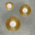 Kinkiet Sun M w kolorze złotym z białym kloszem, posiadający dekoracyjną, teksturowaną ramę z wykończeniem w stylu promieni słonecznych. Widok z góry, trzy elementy o różnych rozmiarach na szarym tle.