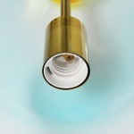 Lampa wisząca Pastello 1xE27 w kolorze złotym, z widocznym gniazdem w kolorze białym. Ujęcie z bliska, pokazujące detal mocowania oraz fakturę materiału. Tło w odcieniach niebieskiego.