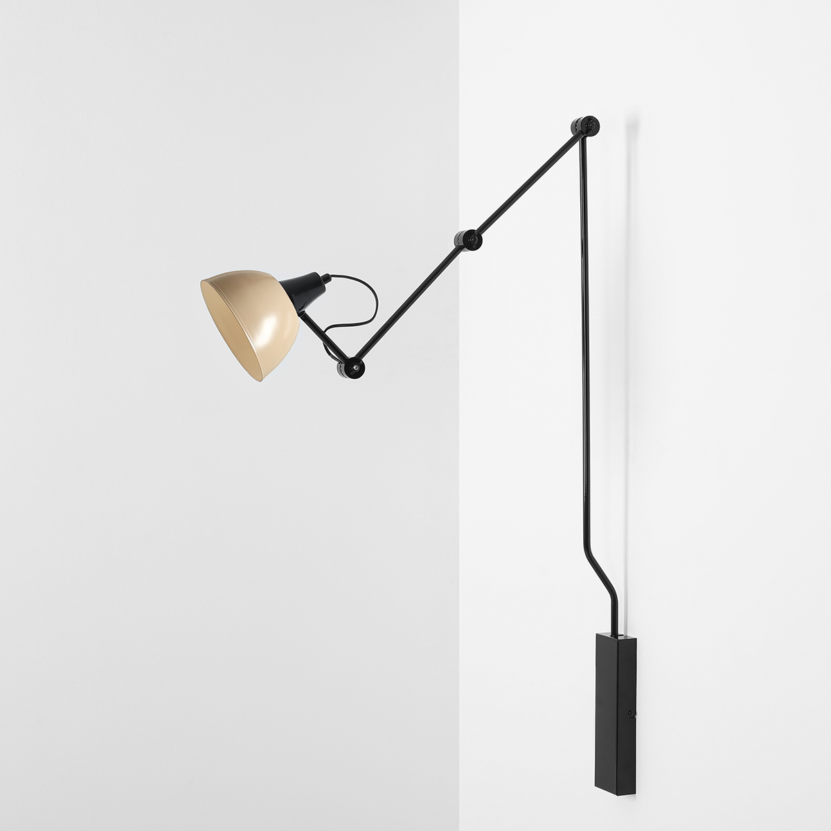 Kinkiet Aida 1xE27 w kolorze czarnym i beżowym, z ruchomą głowicą w kształcie stożka. Montowany na ścianie, z metalowym ramieniem i prostokątną podstawą. Ujęcie z boku, na tle białej ściany.