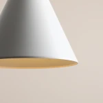 Biała lampa wisząca Form o kształcie stożka, z kloszem matowym na zewnątrz i jasnym wnętrzem. Ujęcie w zbliżeniu na detal klosza, bez widocznych logo czy napisów. Tło w neutralnym kolorze.