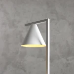 Lampa stołowa Form White z kloszem w kształcie stożka, w kolorze białym, umieszczona na prostokątnej podstawie. Klosz emituje ciepłe światło, a tło jest w odcieniach szarości. Produkt widoczny z boku, ukazujący nowoczesny design.