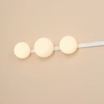 Kinkiet Garda w kolorze białym, z trzema okrągłymi kloszami w odcieniu ciepłej bieli, zamontowany na prostokątnej białej listwie. Klosze są umieszczone w równych odstępach, co tworzy minimalistyczny, nowoczesny design.