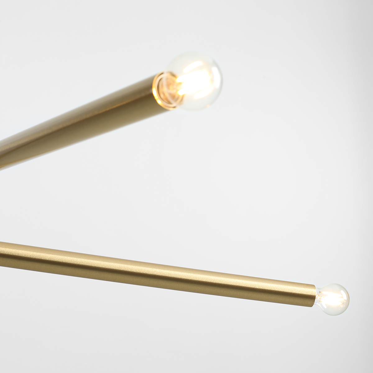 Lampa wisząca Tubo 4-punktowa w kolorze mosiężnym, z czterema prostokątnymi rurkami, każda zakończona kulistą żarówką. Ujęcie z góry, ukazujące detale konstrukcji oraz źródła światła. Tło jasne i jednolite.