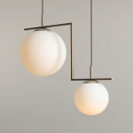 Beżowa lampa wisząca Zac II z dwoma kulistymi kloszami z matowego szkła, zawieszona na minimalistycznym ramieniu. Klosze różnej wielkości, umieszczone w asymetrycznej konfiguracji, na czarnym przewodzie. Tło w jasnym odcieniu.