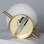 Kinkiet Riccardo-Milano w kolorze złotym z gładką, białą kulą. Ujęcie z tyłu, pokazujące mocowanie i przewody. Metalowa konstrukcja z widocznymi elementami montażowymi. Idealny do nowoczesnych wnętrz.