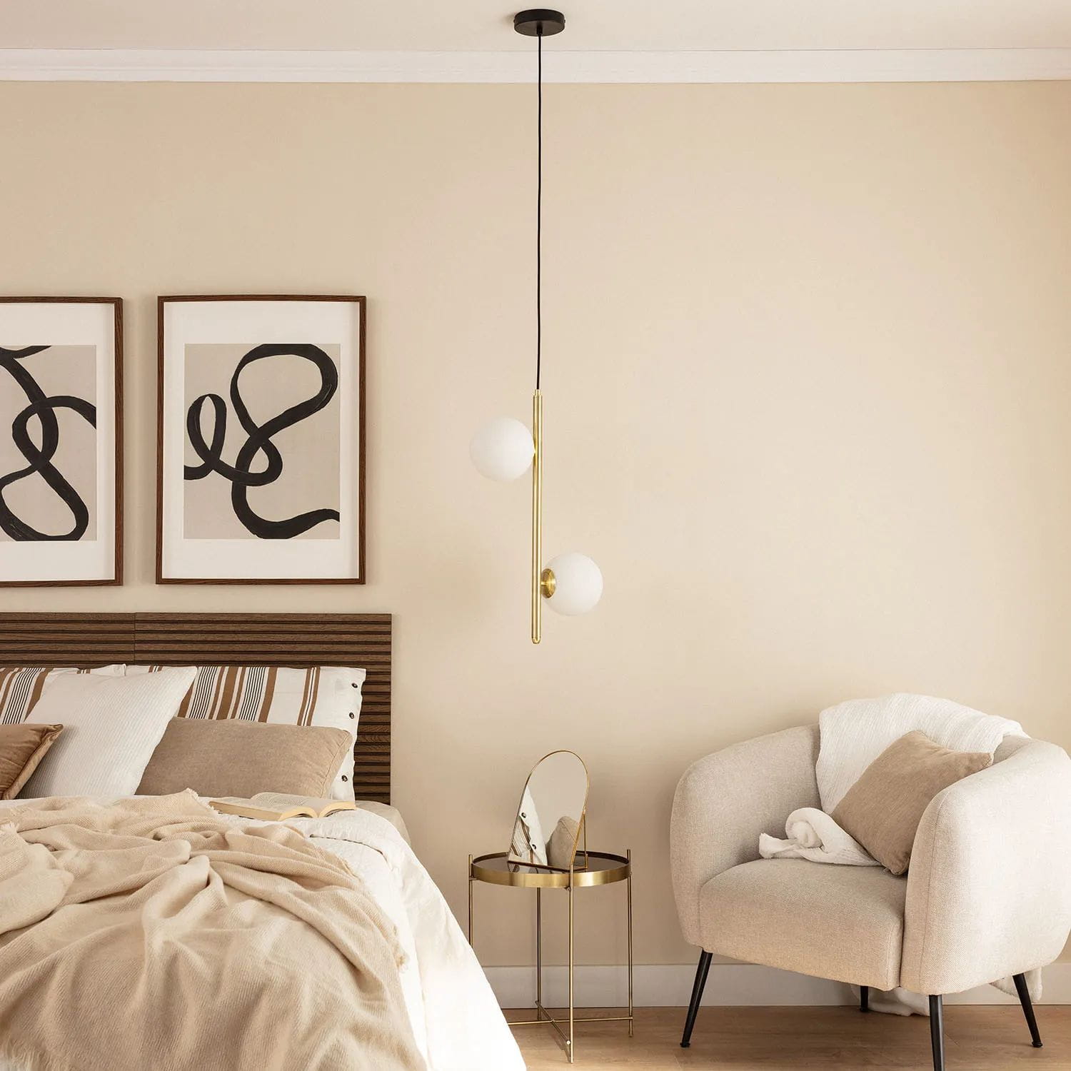 Lampa wisząca Bari-Milano 2xE27 w kolorze złotym, zawieszona na czarnym przewodzie. Posiada dwa białe, okrągłe klosze i proste, minimalistyczne wzornictwo. Zawieszona w nowoczesnej sypialni z jasnymi ścianami i drewnianymi elementami.