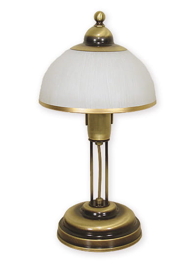 Lampka stołowa Flex O1488 z metalową podstawą w kolorze złotym. Posiada okrągły klosz z białego materiału, z delikatnym wykończeniem. Ujęcie frontalne, lampka stoi na płaskiej powierzchni.