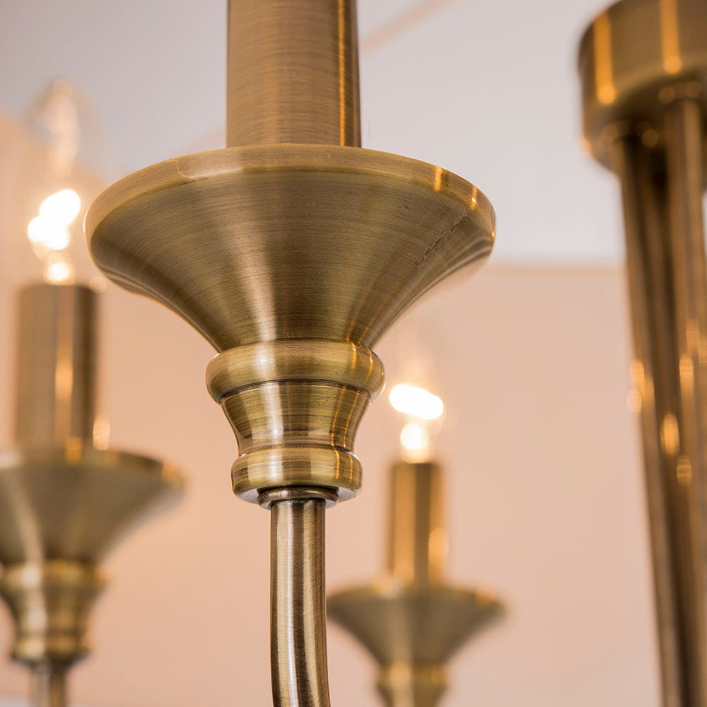 Lampa wisząca Abu Dhabi 6-punktowa w kolorze patyny, z metalowym kloszem o delikatnym, połyskującym wykończeniu. Ujęcie z bliska, ukazujące szczegóły konstrukcji oraz źródła światła w tle.