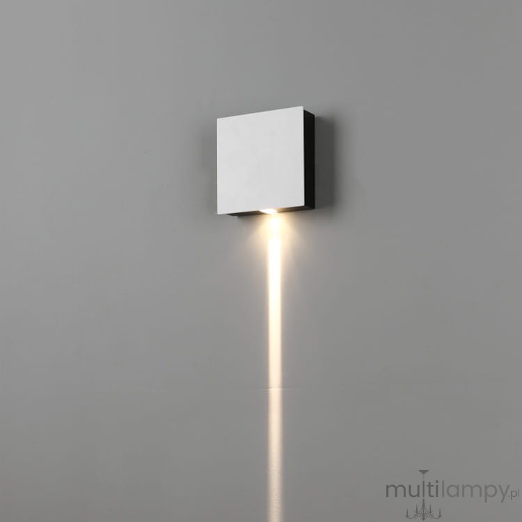 Mollis LED kinkiet 1-punktowy w kwadratowej, metalicznej obudowie, zamontowany na ścianie. Emituje strumień światła w dół, na szarym tle. Prosty design bez widocznych dekoracji czy napisów.