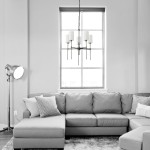 Czarna lampa wisząca Darling z pięcioma kloszami E14, zawieszona na delikatnym łańcuchu. Prosty, elegancki design, umieszczona nad narożnikiem szarej sofy w jasnym wnętrzu.