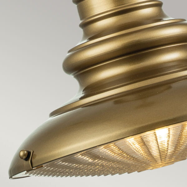 Lampa wisząca ogrodowa Redding Station w antycznym złocie, z widocznym kloszem z przezroczystego materiału i dekoracyjnym detalem. Ujęcie zbliżeniowe na dolną część lampy z żarówką E27, z zamknięciem na boku.