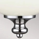 Lampa wisząca Parkman z polerowanego niklu, z okrągłą, mleczną szkłem klosza. Ujęcie z bliska, ukazujące detal mocowania i elegancki kształt podstawy. Idealna do nowoczesnych wnętrz.