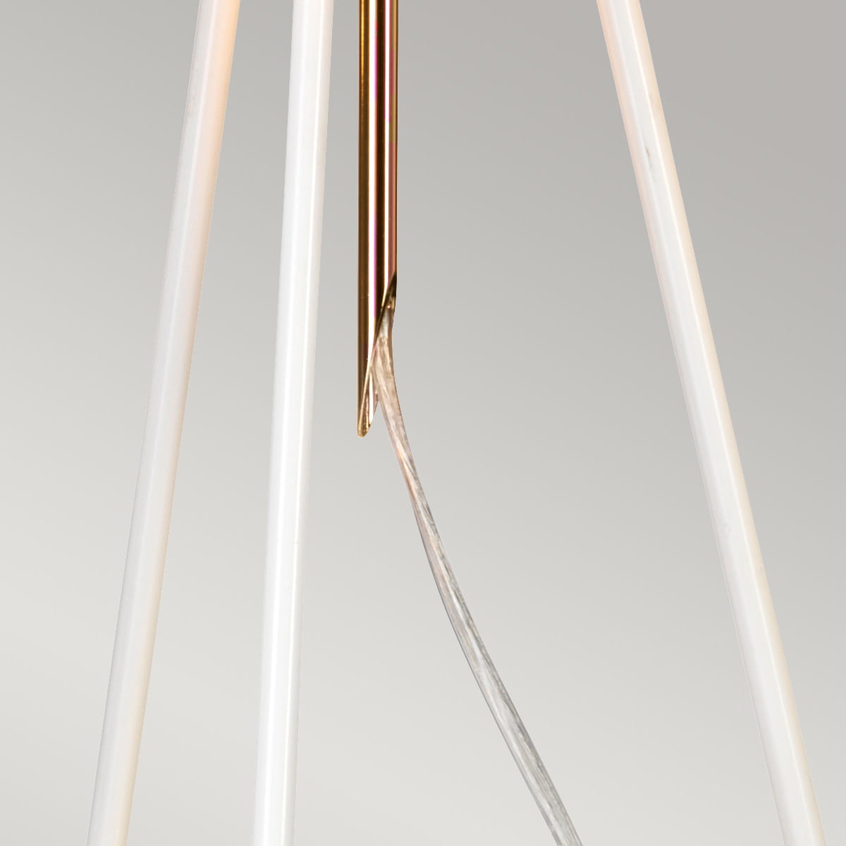 Biało-złota lampka stołowa Ferrara z oprawą E27, z metalowym detalem w kolorze złotym i białymi, transparentnymi nogami. Widoczny przewód elektryczny. Produkt ustawiony w pozycji pionowej, na jednolitym tle.