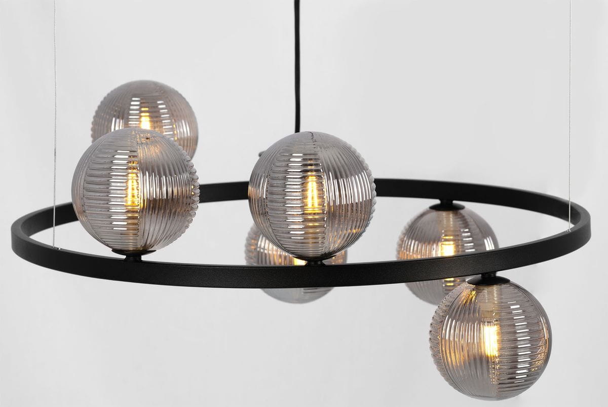 Lampa wisząca Monza z sześcioma żarówkami G9. Konstrukcja w kolorze czarnym z matowym okręgiem, na którym zawieszone są przezroczyste, teksturowane klosze w odcieniu grafitowym. Ujęcie z boku, ukazujące detale kloszy i ich źródła światła.