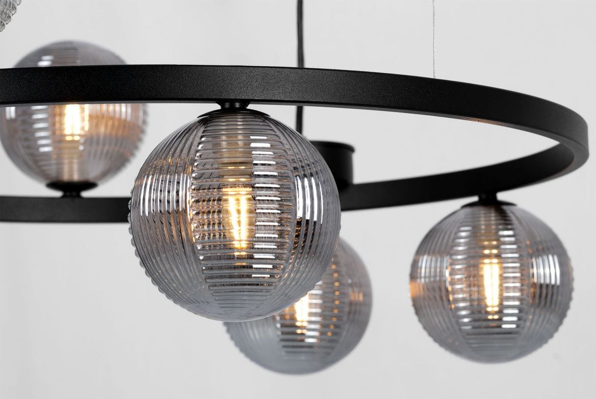 Lampa wisząca Monza w kolorze czarnym i grafitowym z sześcioma kloszami G9. Klosze w formie kul z przezroczystego, żebrowanego szkła, zamontowane na okrągłej, metalowej konstrukcji. Oświetlenie w górnej części, z lekkim błyskiem.