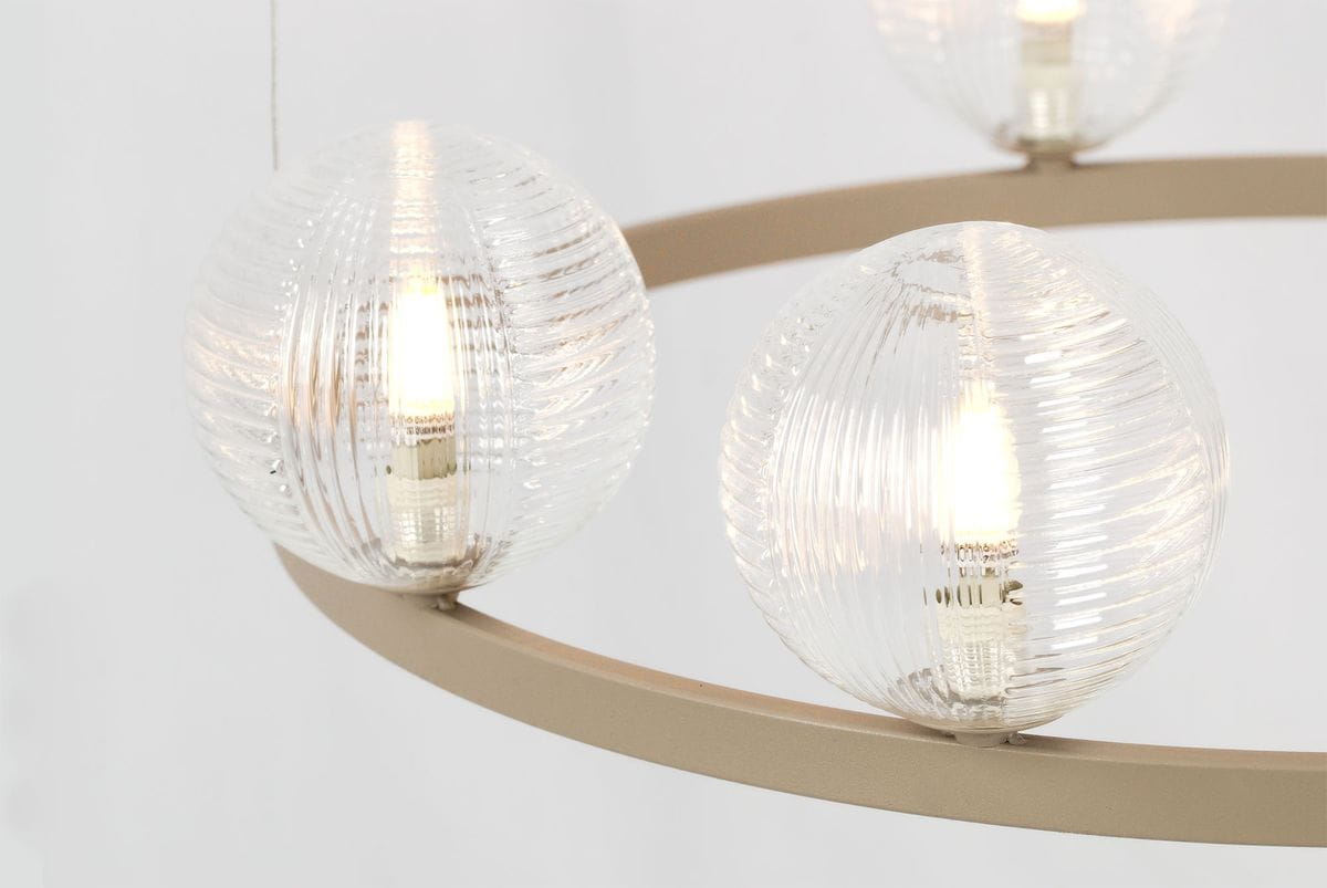 Lampa wisząca Tesoro z sześcioma kulistymi kloszami w kolorze przezroczystym, wykonanymi ze szkła o żłobionej fakturze. Metalowa, beżowa rama z okrągłym kształtem, wizualizacja zbliżona na detale kloszy z ciepłym światłem wewnątrz.