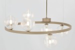 Lampa wisząca Tesoro w kolorze beżowym, z przezroczystymi szklanymi kloszami w kształcie kul, zawieszona na okrągłym stelażu. Zestaw sześciu źródeł światła G9, z metalowym mocowaniem na suficie. Tło jasne, minimalistyczne.