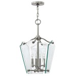 Lampa wisząca Wingate S w kolorze polerowanego niklu, z przezroczystym kloszem w kształcie sześciokąta, zawierająca cztery gniazda E14. Ujęcie z boku, zawieszona na łańcuchu, z widocznymi detalami mocowania i eleganckim wykończeniem.