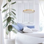 Lampa wisząca LED Alchemy o mocy 49W i barwie światła 3000K w kolorze złotym, umieszczona nad sofą. Okrągła, płaska konstrukcja z delikatnym wzorem na kloszu. W tle widoczne rośliny oraz poduszki w odcieniach niebieskiego i białego.