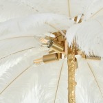 Lampa wisząca Emu 6xE14 w kolorze złotym i białym, z ozdobami z piór. Kąt ujęcia z góry, pokazujący detal mocowania oraz żarówki. Złoty trzonek i białe pióra tworzą elegancki wygląd.