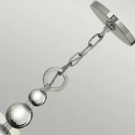 Lampa wisząca Zelda w polerowanym niklu, z łańcuchowym zawieszeniem. U góry okrągły stelaż z metaliczną powierzchnią, poniżej trzy błyszczące kuliste elementy i metalowe okręgi. Idealna do nowoczesnych wnętrz.