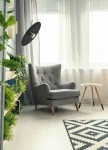 Lampa wisząca Burgas D45 w kolorze czarnym z złotym detalem, zawieszona nad szarym fotelem. Kształt okrągły, z widoczną oprawą na żarówkę GX53. Otoczenie z roślinnością i jasnym tłem okna.