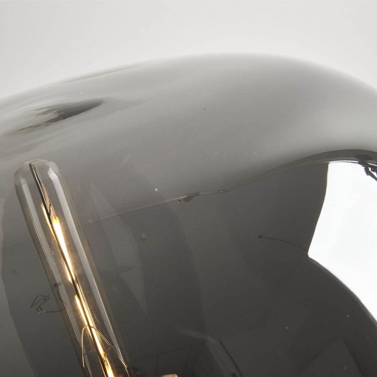 Block lampa stołowa 1xE27 w kolorze czarnym, z gładką, błyszczącą powierzchnią. Ujęcie z bliska na klosz, z widocznym żarnikiem w środku. Lampa ma zaokrąglony kształt, co podkreśla jej nowoczesny styl. Tło jasne, neutralne.