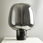 Lampa stołowa Block 1xE27 w kolorze czarnym, z dużym, przezroczystym kloszem o zaokrąglonym kształcie. Widoczna lampa wewnętrzna z żarówką LED. Ustawiona na białym blacie, z kablem elektrycznym wychodzącym z podstawy.