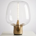 Lampa stołowa Block 1xE27 w kolorze złotym, z przezroczystym kloszem i metalową podstawą. Ujęcie frontalne, ukazujące prostą linię światła LED. Produkt stoi na białym tle, podkreślając elegancki design.